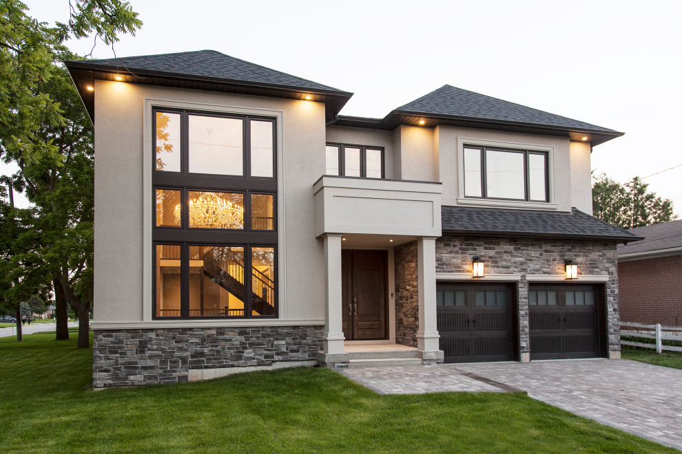 Inspiration for a large transitional gray two-story stone house exterior remodel in Toronto with a shingle roof and a gray roof