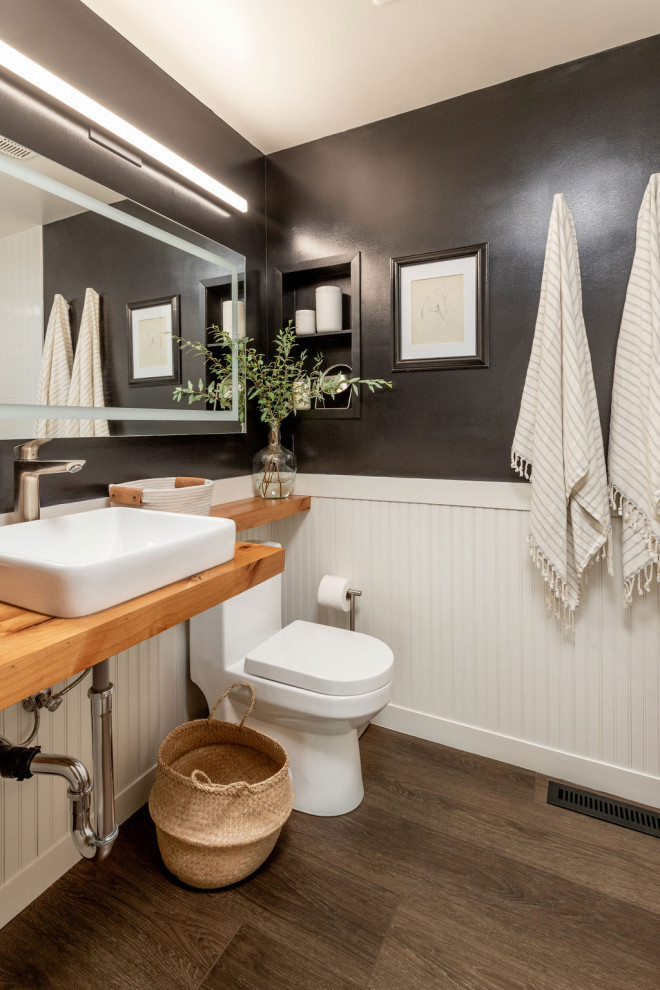 Exempel på ett mellanstort amerikanskt brun brunt badrum med dusch, med skåp i ljust trä, en toalettstol med hel cisternkåpa, svarta väggar, vinylgolv, ett integrerad handfat, träbänkskiva och brunt golv