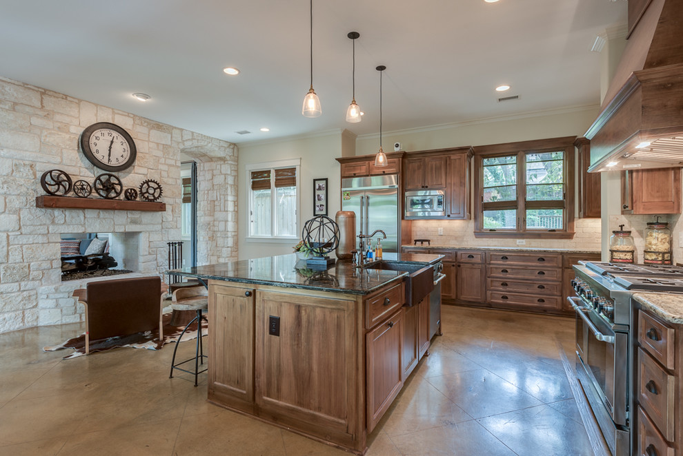 Example of a mid-sized transitional l-shaped concrete floor eat-in kitchen design in Dallas with a farmhouse sink, shaker cabinets, medium tone wood cabinets, granite countertops, beige backsplash, stone tile backsplash, stainless steel appliances and an island