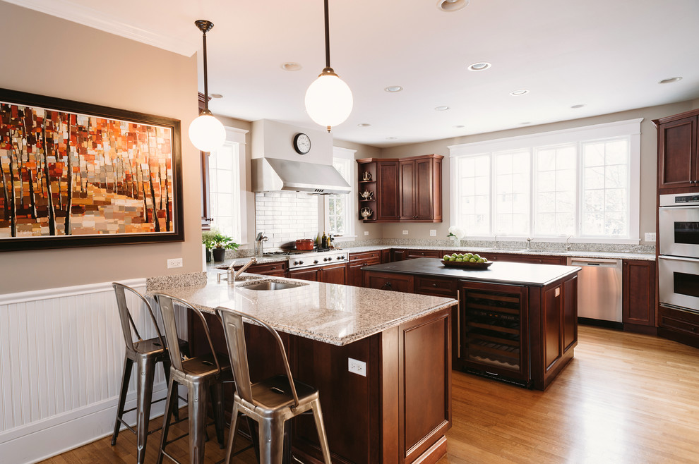 Eat-in kitchen - large transitional u-shaped medium tone wood floor eat-in kitchen idea with recessed-panel cabinets, brown cabinets, granite countertops, metallic backsplash, subway tile backsplash, stainless steel appliances and gray walls