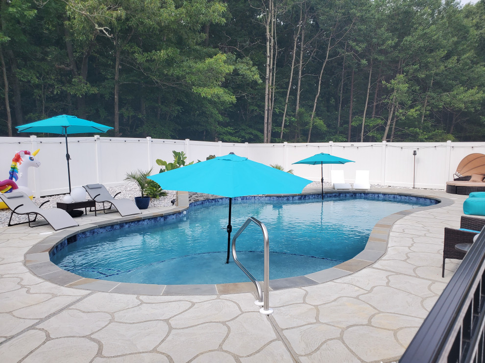Modelo de piscina clásica de tamaño medio a medida en patio trasero con losas de hormigón
