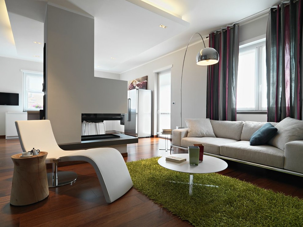 Design ideas for a large modern open concept living room in Turin with white walls, medium hardwood floors, a two-sided fireplace, a plaster fireplace surround and a freestanding tv.