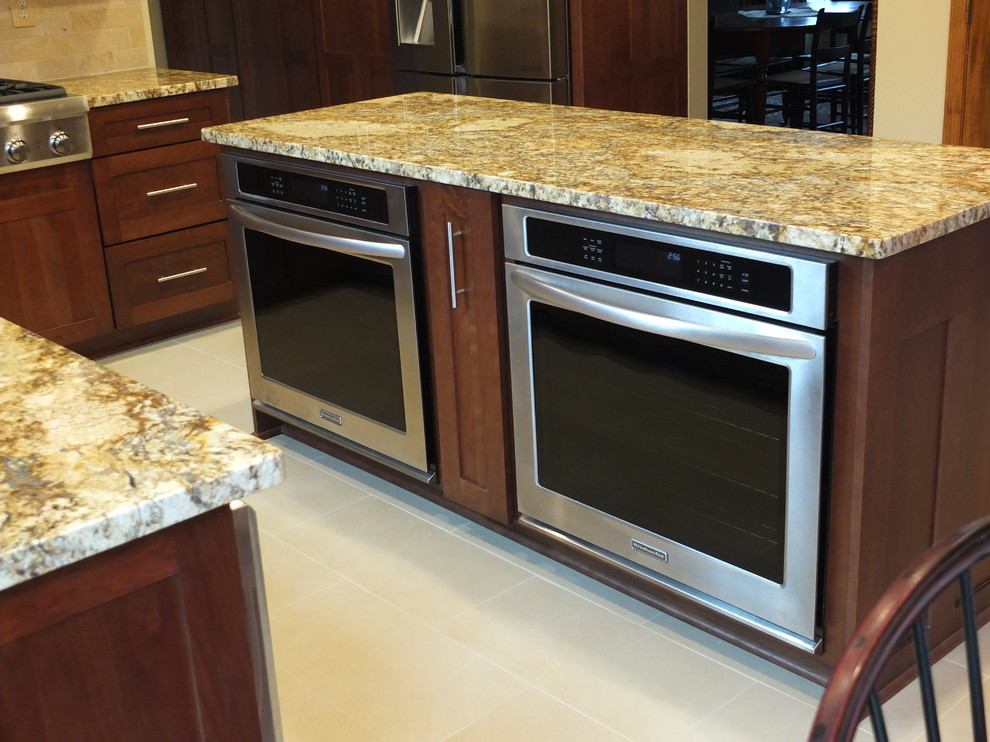 Eat-in kitchen - mid-sized transitional l-shaped ceramic tile eat-in kitchen idea in Columbus with an undermount sink, shaker cabinets, brown cabinets, granite countertops, beige backsplash, ceramic backsplash, stainless steel appliances and an island