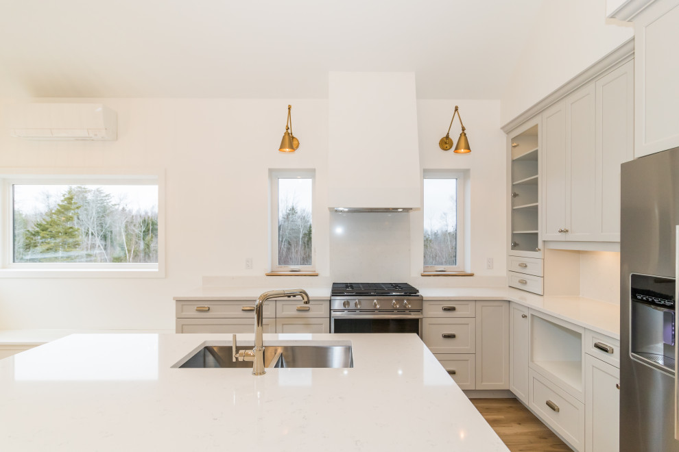 Example of a mid-sized l-shaped light wood floor and brown floor kitchen design with recessed-panel cabinets, blue cabinets, quartzite countertops, stainless steel appliances, an island and white countertops