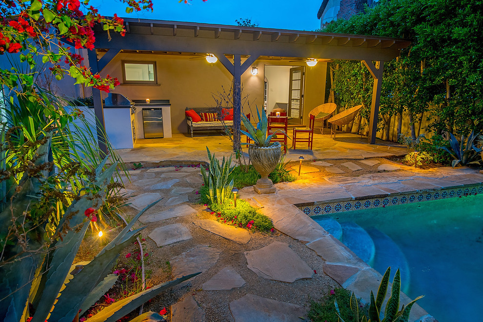 This is an example of a mid-sized mediterranean backyard full sun xeriscape for summer in Los Angeles with natural stone pavers.
