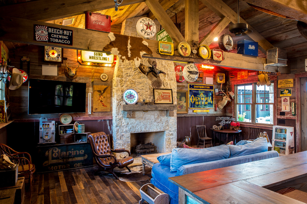 Inspiration for a rustic enclosed dark wood floor home design remodel in Austin with a standard fireplace, a stone fireplace, a wall-mounted tv, a bar and brown walls