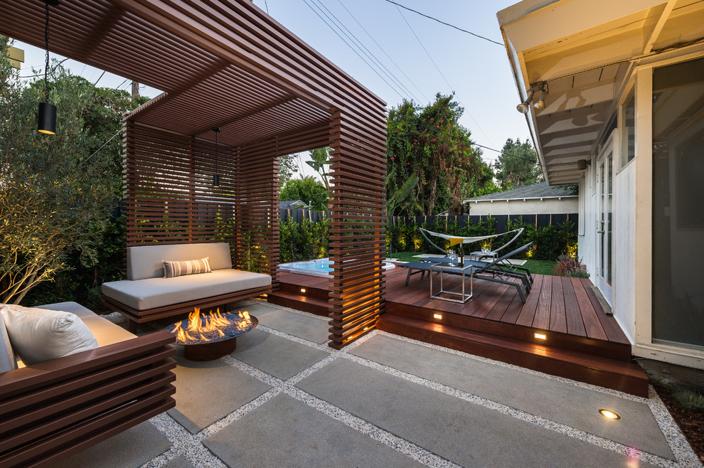 This is an example of a small contemporary backyard deck in Los Angeles with a fire feature and a pergola.