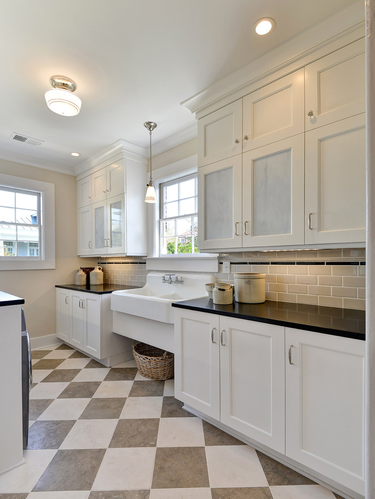 Large transitional galley utility room in Charleston with an utility sink, recessed-panel cabinets, white cabinets, solid surface benchtops, beige walls, a side-by-side washer and dryer, multi-coloured floor and black benchtop.