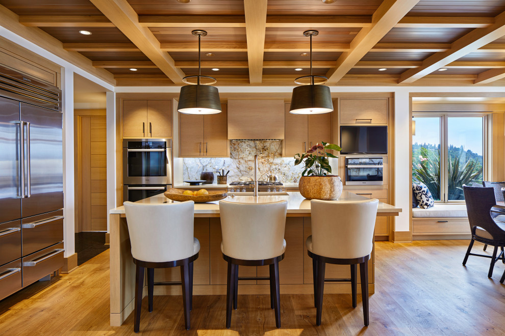 This is an example of a large transitional l-shaped open plan kitchen in Seattle with an undermount sink, flat-panel cabinets, medium wood cabinets, grey splashback, stainless steel appliances, medium hardwood floors, with island, brown floor, beige benchtop, exposed beam, wood, solid surface benchtops and granite splashback.