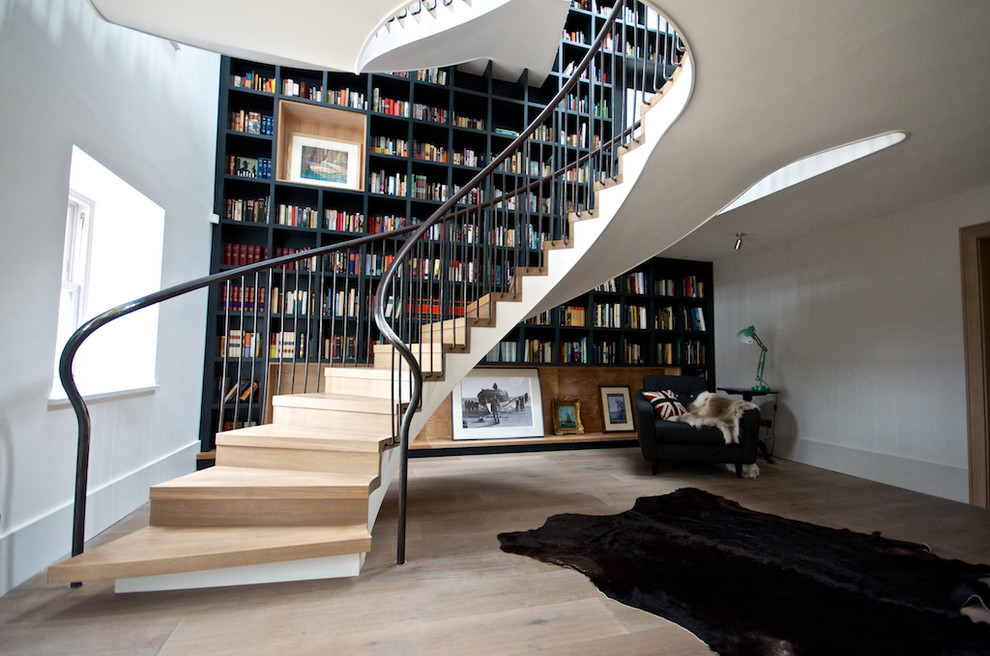 This is an example of an expansive contemporary wood curved staircase in Kent with wood risers.