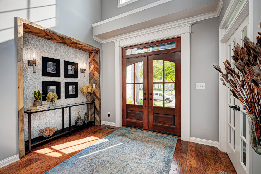 Cette image montre une porte d'entrée design de taille moyenne avec une porte double, une porte en verre, un mur gris, parquet clair et un sol marron.