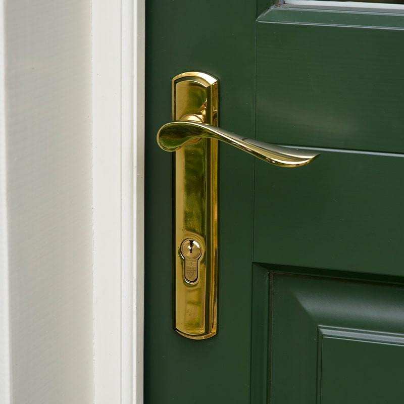 Cette image montre une porte d'entrée traditionnelle avec une porte simple et une porte verte.