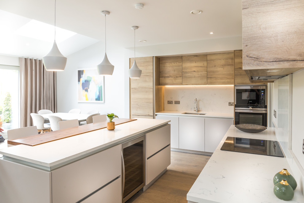 Design ideas for a mid-sized contemporary galley open plan kitchen in Other with a single-bowl sink, flat-panel cabinets, light wood cabinets, quartzite benchtops, white splashback, stone slab splashback, stainless steel appliances, light hardwood floors and with island.