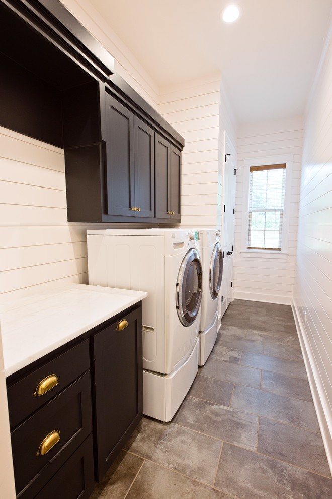 Transitional single-wall dedicated laundry room with shaker cabinets, blue cabinets, white walls, porcelain floors, a side-by-side washer and dryer and grey floor.
