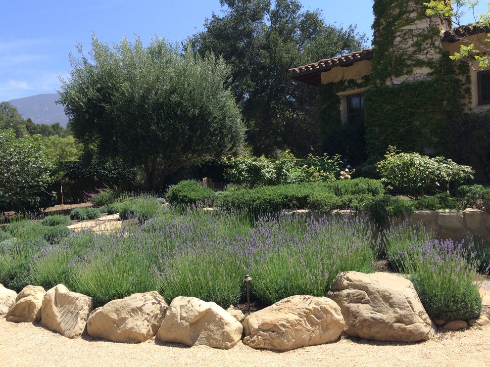 Design ideas for a large mediterranean full sun driveway for summer in Santa Barbara with a water feature and gravel.
