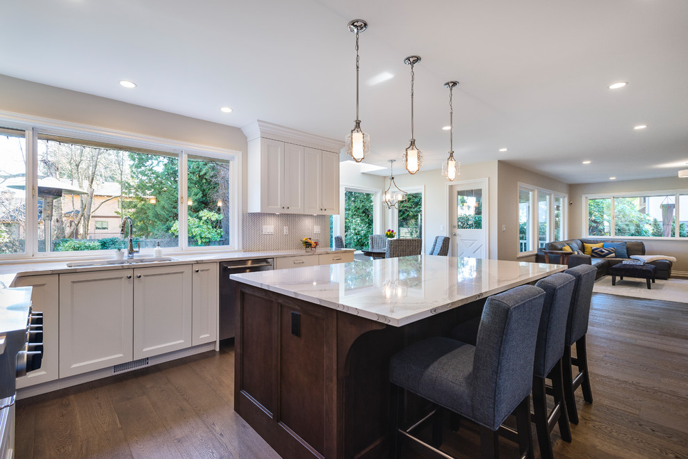 Eat-in kitchen - large transitional u-shaped medium tone wood floor and brown floor eat-in kitchen idea in Vancouver with an undermount sink, recessed-panel cabinets, white cabinets, quartz countertops, white backsplash, mosaic tile backsplash, stainless steel appliances and an island