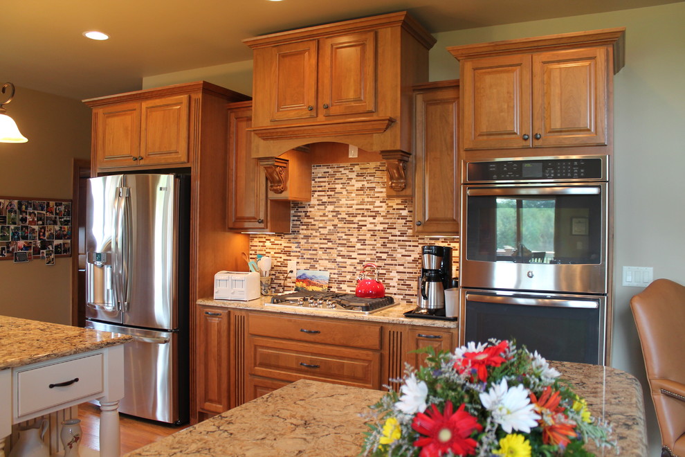 Inspiration for a large single-wall eat-in kitchen remodel with an undermount sink, raised-panel cabinets, medium tone wood cabinets, solid surface countertops, stainless steel appliances, beige walls and an island