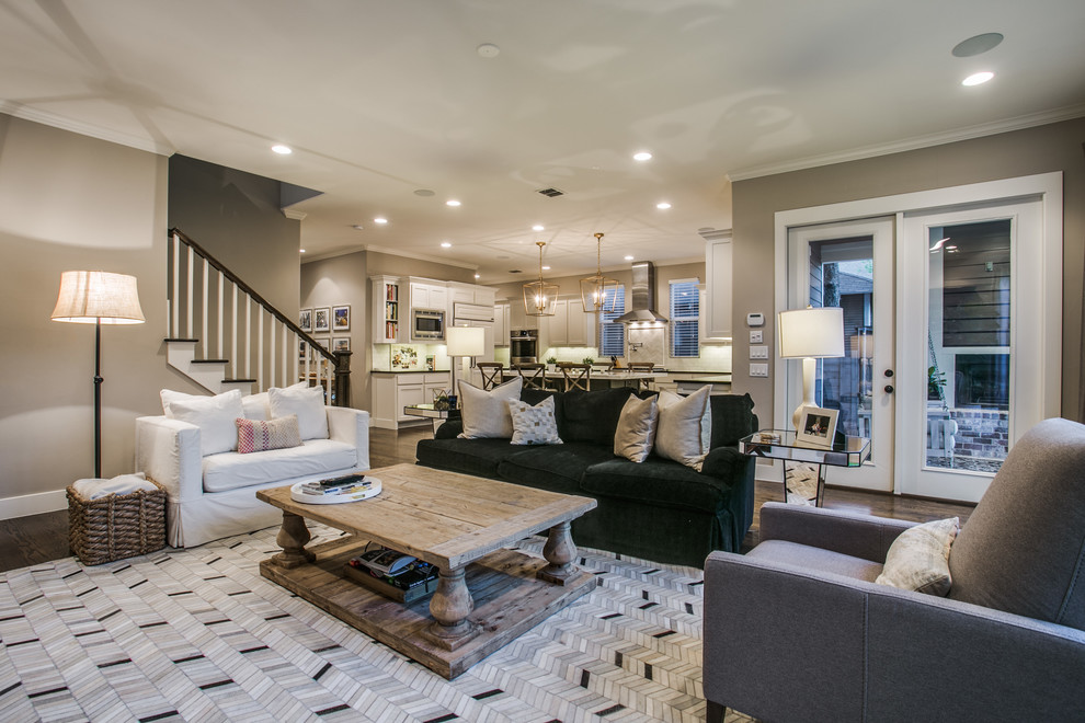 This is an example of a large contemporary formal open concept living room in Dallas with beige walls, medium hardwood floors, a standard fireplace, a wood fireplace surround, a wall-mounted tv and brown floor.
