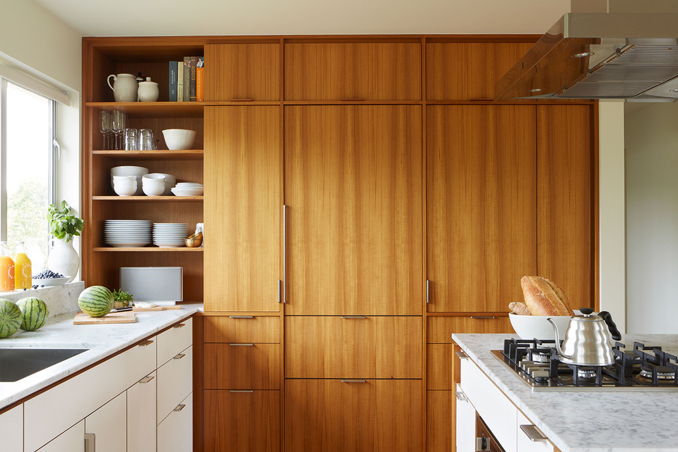 Small midcentury l-shaped open plan kitchen in Seattle with a single-bowl sink, flat-panel cabinets, medium wood cabinets, marble benchtops, white splashback, stone slab splashback, panelled appliances, medium hardwood floors, with island and brown floor.