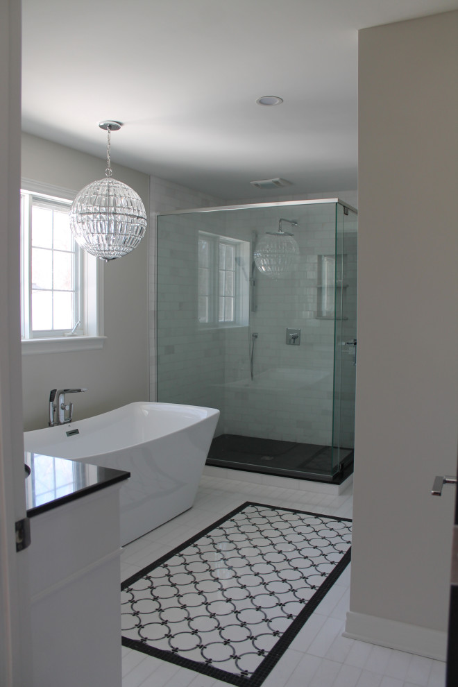 Photo of a large transitional master bathroom in Montreal with white cabinets, a freestanding tub, a corner shower, a one-piece toilet, white tile, porcelain tile, grey walls, marble floors, an undermount sink, quartzite benchtops, white floor, a hinged shower door, black benchtops, a double vanity and a freestanding vanity.