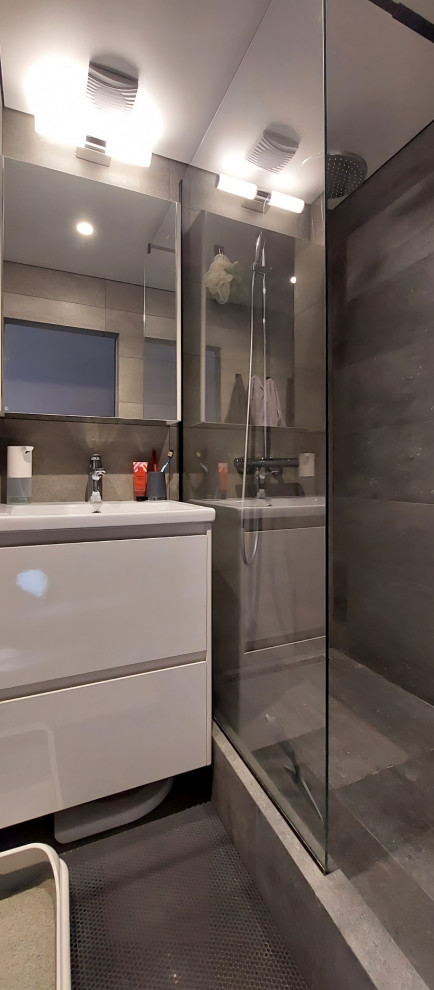 На фото: маленькая серо-белая ванная комната в современном стиле с плоскими фасадами, белыми фасадами, душем в нише, инсталляцией, серой плиткой, керамогранитной плиткой, серыми стенами, полом из керамогранита, душевой кабиной, накладной раковиной, серым полом, шторкой для ванной, гигиеническим душем, тумбой под одну раковину и подвесной тумбой для на участке и в саду с