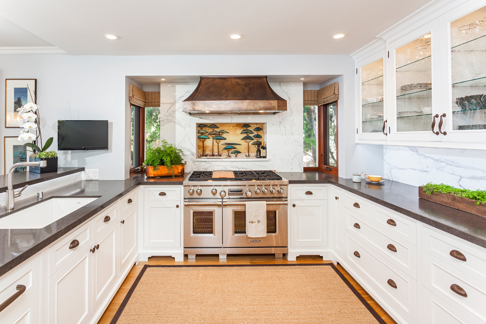 Photo of a traditional u-shaped kitchen in Salt Lake City with an undermount sink, white cabinets, white splashback, stainless steel appliances, no island and glass-front cabinets.