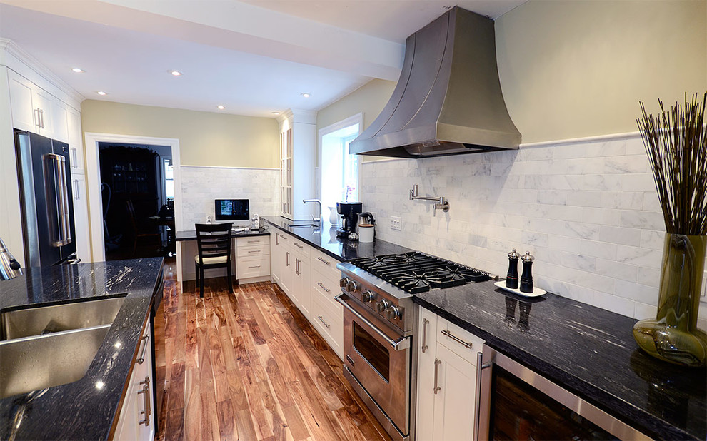 Eat-in kitchen - mid-sized transitional l-shaped medium tone wood floor eat-in kitchen idea in Toronto with a double-bowl sink, raised-panel cabinets, white cabinets, solid surface countertops, black backsplash, stone slab backsplash, stainless steel appliances and an island