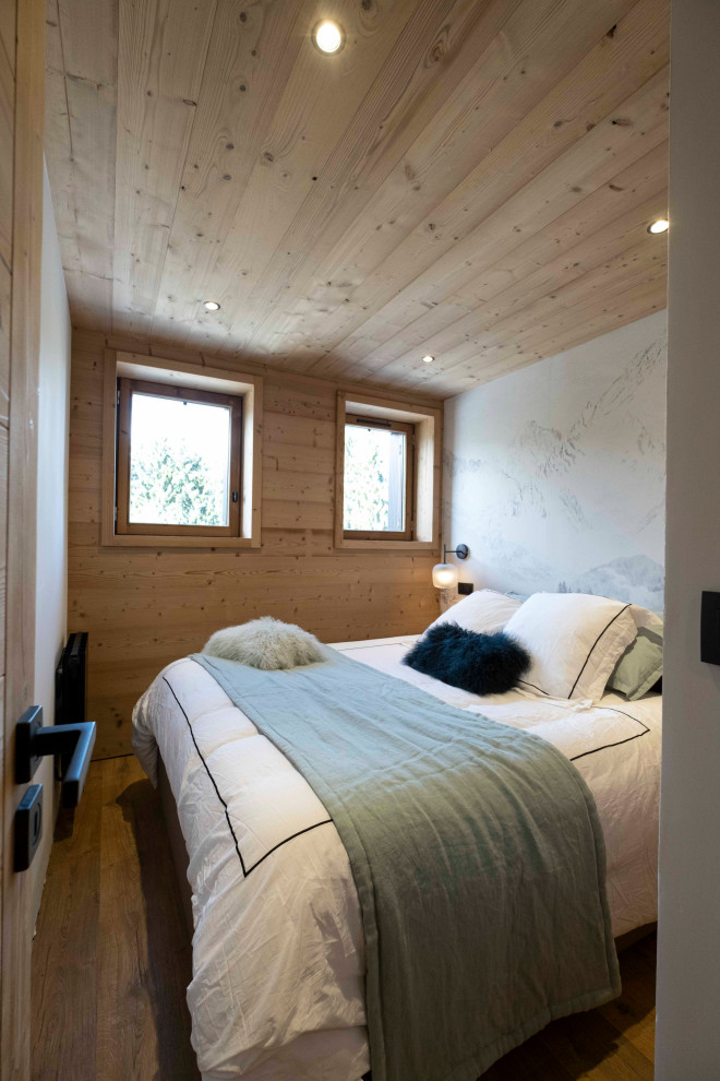 Diseño de dormitorio principal y blanco y madera rústico pequeño sin chimenea con paredes blancas, suelo laminado, suelo marrón, madera y madera
