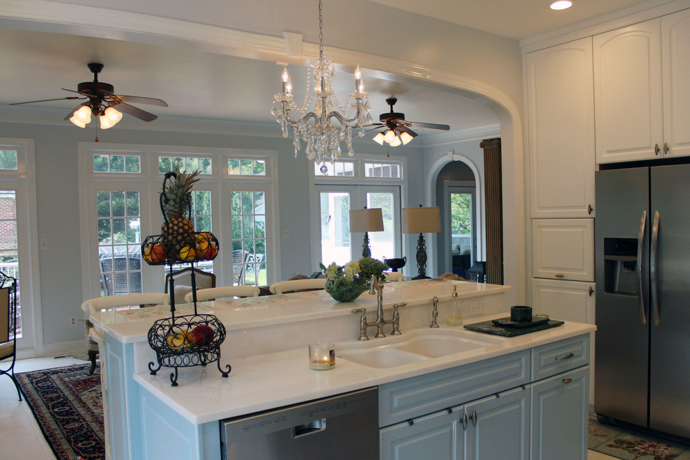 Photo of a mid-sized traditional u-shaped open plan kitchen in Raleigh with a double-bowl sink, raised-panel cabinets, white cabinets, quartzite benchtops, white splashback, glass tile splashback, stainless steel appliances, brick floors and with island.