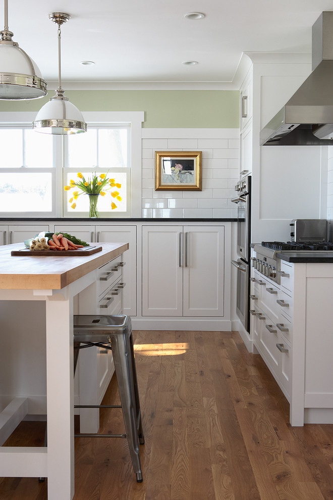 Large traditional eat-in kitchen in Minneapolis with shaker cabinets, white cabinets, white splashback, subway tile splashback, stainless steel appliances, a farmhouse sink, granite benchtops, medium hardwood floors and with island.