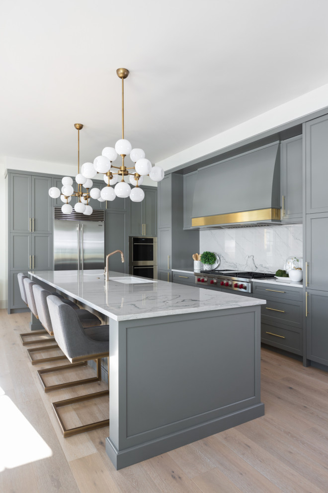 Eat-in kitchen - large transitional l-shaped light wood floor eat-in kitchen idea in Calgary with an undermount sink, quartzite countertops, gray backsplash, stainless steel appliances, an island and gray countertops
