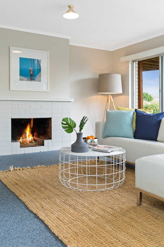 Photo of a beach style living room in Hobart with grey walls, a standard fireplace, a brick fireplace surround and no tv.