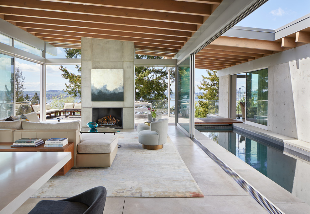 Expansive contemporary formal open concept living room in Seattle with grey walls, concrete floors, a standard fireplace, a concrete fireplace surround, a concealed tv and grey floor.