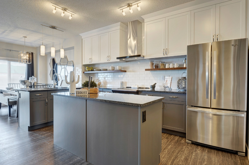 Inspiration for a mid-sized transitional l-shaped vinyl floor and black floor eat-in kitchen remodel in Edmonton with an undermount sink, shaker cabinets, gray cabinets, granite countertops, white backsplash, subway tile backsplash, stainless steel appliances and an island