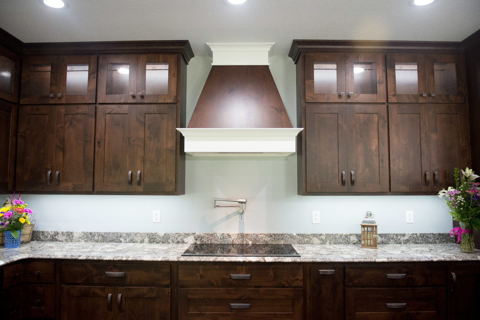 Example of a transitional l-shaped open concept kitchen design with an undermount sink, shaker cabinets, dark wood cabinets, granite countertops, stainless steel appliances, an island and multicolored countertops