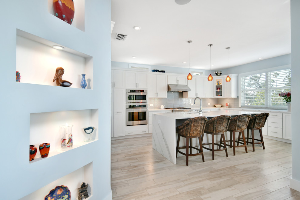 Example of a mid-sized transitional u-shaped porcelain tile and gray floor open concept kitchen design in Tampa with a double-bowl sink, recessed-panel cabinets, white cabinets, marble countertops, gray backsplash, cement tile backsplash, stainless steel appliances and an island