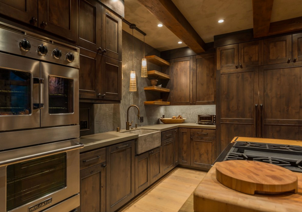 Open concept kitchen - rustic l-shaped open concept kitchen idea with a farmhouse sink, recessed-panel cabinets, dark wood cabinets, stainless steel appliances and an island