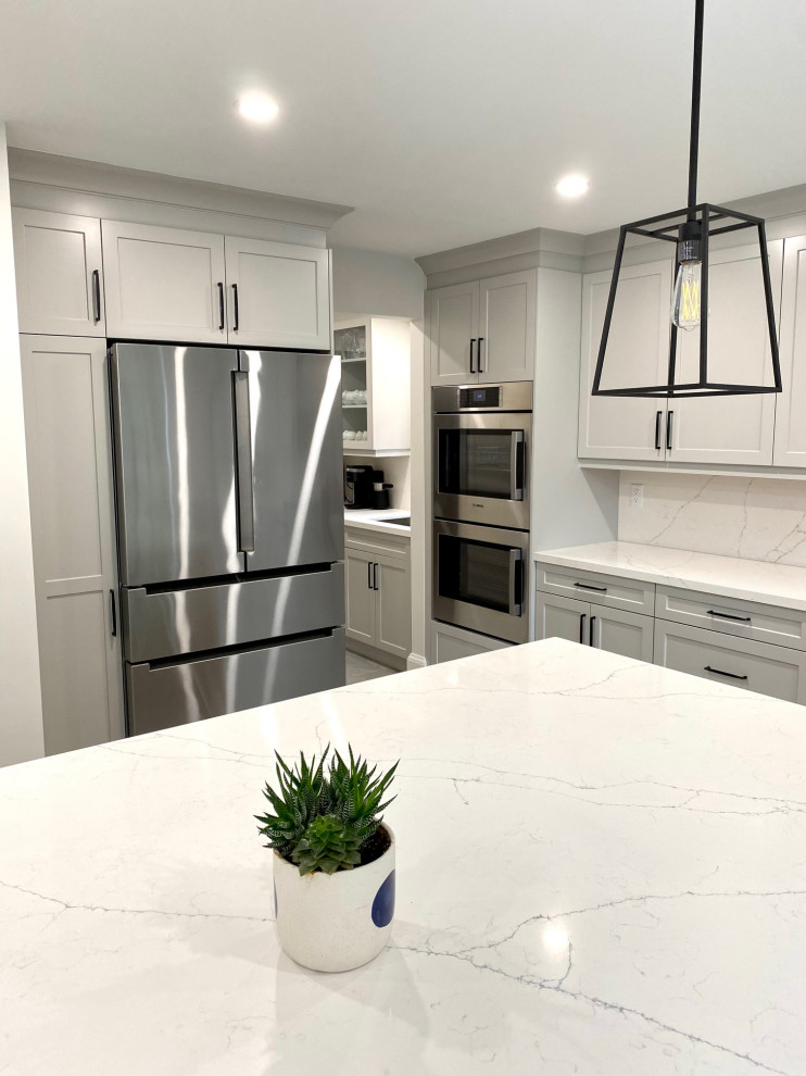Example of a mid-sized transitional l-shaped porcelain tile open concept kitchen design in Toronto with an undermount sink, shaker cabinets, gray cabinets, quartz countertops, white backsplash, quartz backsplash, stainless steel appliances, an island and white countertops