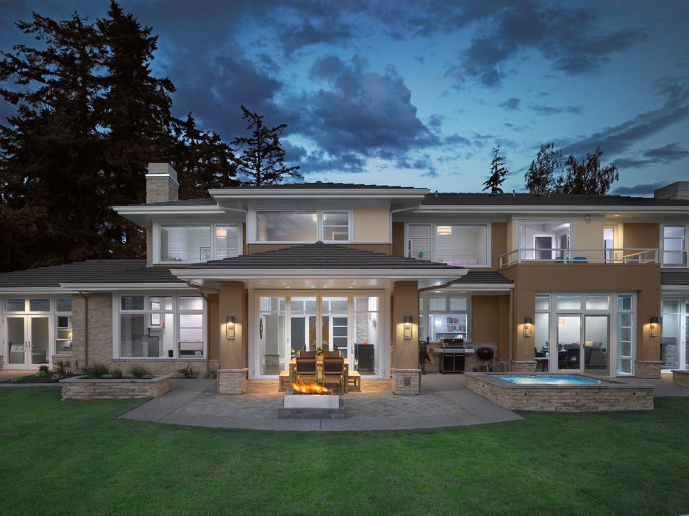 This is an example of a large contemporary two-storey stucco grey house exterior in Seattle with a hip roof and a shingle roof.