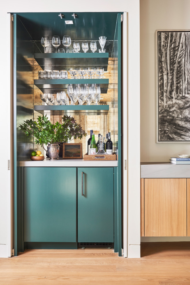 Contemporary single-wall home bar in Dallas with flat-panel cabinets, green cabinets, mirror splashback, medium hardwood floors, brown floor and white benchtop.