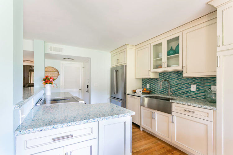 Photo of a small beach style galley eat-in kitchen in Charleston with a farmhouse sink, beaded inset cabinets, beige cabinets, glass benchtops, blue splashback, ceramic splashback, stainless steel appliances, medium hardwood floors, with island and multi-coloured benchtop.