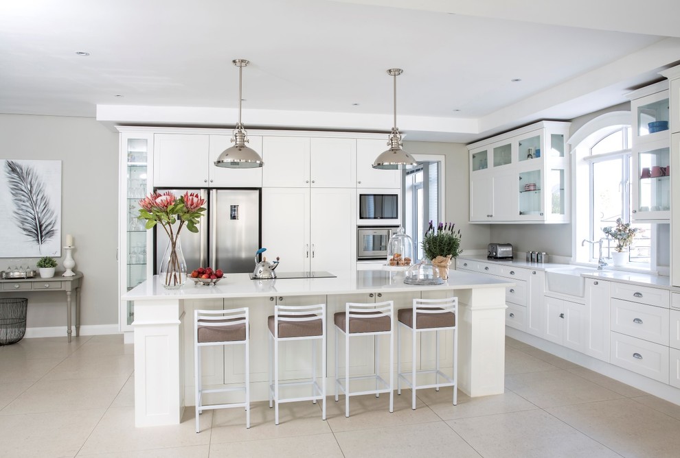 Design ideas for a large transitional l-shaped open plan kitchen in Other with a farmhouse sink, shaker cabinets, white cabinets, quartz benchtops, stainless steel appliances, porcelain floors and with island.