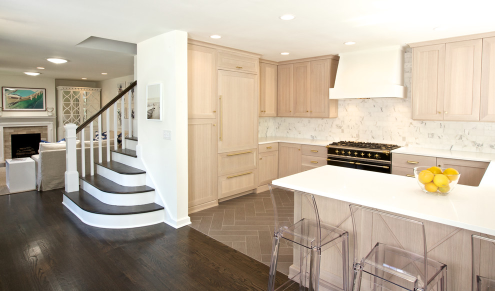 This is an example of a mid-sized transitional u-shaped open plan kitchen in Atlanta with an undermount sink, shaker cabinets, light wood cabinets, quartz benchtops, white splashback, marble splashback, black appliances, porcelain floors, a peninsula, brown floor and white benchtop.