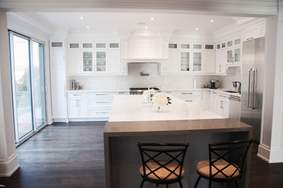 Enclosed kitchen - large transitional l-shaped dark wood floor and brown floor enclosed kitchen idea in Toronto with an undermount sink, shaker cabinets, white cabinets, quartz countertops, white backsplash, marble backsplash, stainless steel appliances, an island and white countertops