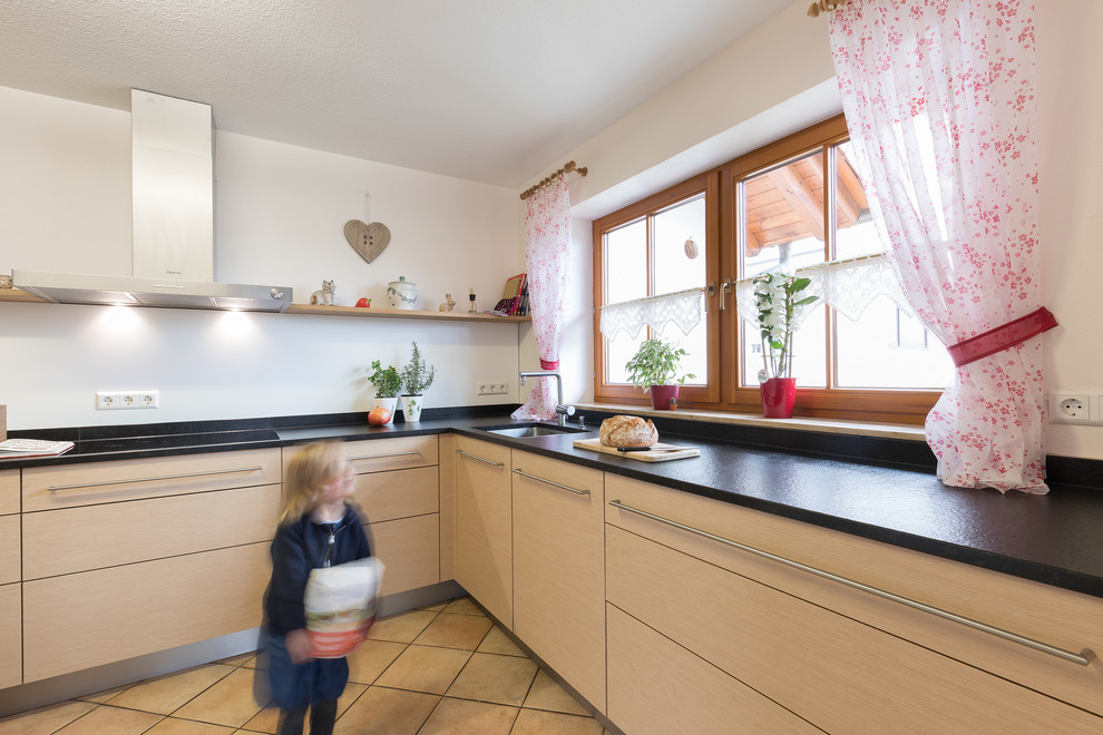 Photo of a mid-sized country u-shaped separate kitchen in Stuttgart with granite benchtops, no island, medium wood cabinets and black benchtop.