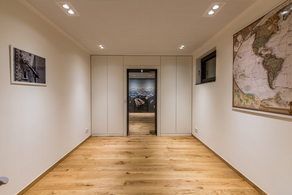 Mittelgroßes Industrial Untergeschoss mit weißer Wandfarbe, braunem Holzboden und braunem Boden in Sonstige