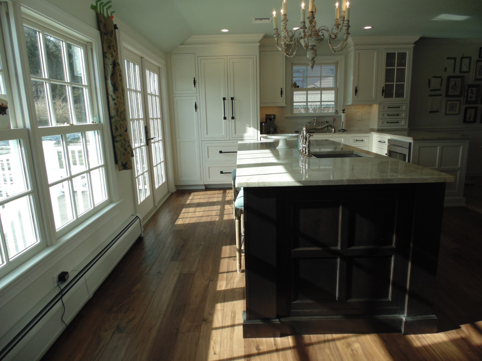 Inspiration for a large transitional u-shaped medium tone wood floor and brown floor eat-in kitchen remodel with an undermount sink, recessed-panel cabinets, white cabinets, quartzite countertops, beige backsplash, subway tile backsplash, stainless steel appliances, an island and beige countertops