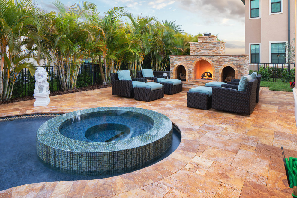 Large arts and crafts backyard custom-shaped pool in Miami with a water feature and natural stone pavers.