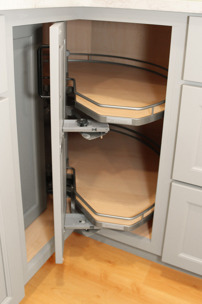 Inspiration for a large transitional u-shaped light wood floor and brown floor enclosed kitchen remodel in Boston with a double-bowl sink, shaker cabinets, gray cabinets, quartz countertops, white backsplash, porcelain backsplash, black appliances, an island and white countertops