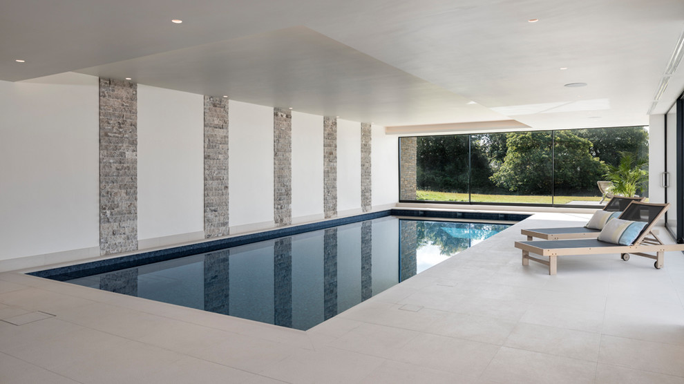 Design ideas for a large modern indoor rectangular lap pool in London with a pool house.